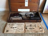 Full view of open wood box containing all parts and paper instructions in front.