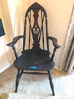 Full front view of vintage wooden armchair showing carved details and turned legs.