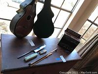 Table display of accordion, cases, harmonicas, flute parts and baton on wooden cabinet