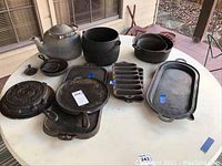 Overview of all cookware items on table, including kettles, skillets, griddles, molds