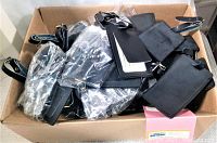 Box containing multiple new black leather luggage tags with buckle straps.