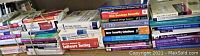 Photo of stacked software development and programming books showing a variety of titles and subjects including Java, web services, and software testing.