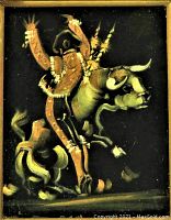 Close-up photo of black velvet painting showing matador riding a bull in gold and brown tones on black velvet