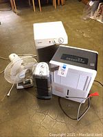 All four items: white Kenmore dehumidifier, white Kenmore portable air conditioner, vertical black and silver Lasko oscillating ceramic heater, and white Lasko oscillating pedestal fan on floor