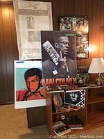 Wide view of the collectors' display with Malcolm X and Muhammad Ali posters, books and framed photos on wooden shelves