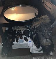 Large round wall mirror with dark metal frame seen from above on a table surface.