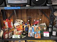 Photo of assorted adhesives, wall hooks, electrical tape, and Panasonic cordless phones arranged on a garage shelving unit.