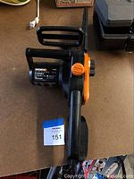 Side view of the electric pole saw showing the motor housing, handle and orange knob.