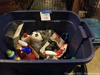 Large blue plastic bin containing assorted pet care products, including two Kong chew toys in packaging and various spray bottles of cleaning and deodorizing products.