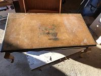 Top view of the rectangular coffee table showing worn surface with faded floral design and discoloration.