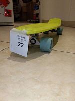 Yellow Penny Board skateboard angled to show side and underside with blue wheels and trucks.