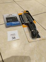 Yukon Gear survival knife in packaging with sheath alongside Tool Logic credit card-sized multi-tool in plastic packaging with label.