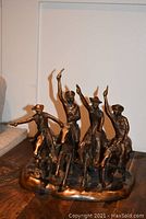 Front view of full sculpture showing four cowboys on galloping horses.