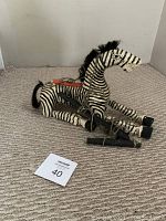 Zebra marionette laid on carpet showing full body horizontal position with reins and black hooves.