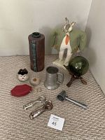 Full lot showing all items arranged on carpet, including pottery, folk-art bunny, fishing float on wood stand, bar accessories and jewellery clutch.