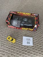 NASCAR Collector Series 1:24 Dodge die-cast car displayed in original box with yellow Porsche Carrera GT car placed beside it on carpet.