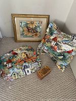 Overall view of the lot showing the framed picture, pillow, placemats, and playing card holder on carpeted floor