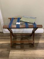 Front view of the wooden suitcase stand with the packaged twin flat sheet placed on top.