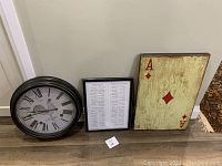 Photo showing all three items in the lot together: round rooster clock, framed quotes print, and Ace of Diamonds print
