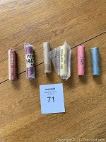 Six rolls of coins arranged on wooden floor: Pennies 1963, 1967 (two rolls), 1940, 1965, and 1967 nickels.