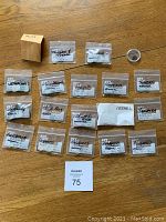 Photo showing 19 labeled coin pouches including Australia, Netherlands, Israel, Germany, Venezuela, among others. One small box labeled 'Swisse' and a coin magnifier loupe present.