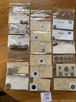 Multiple bags and envelopes containing international coins labeled by country including Euro, France, Thailand, Ecuador, U.S.