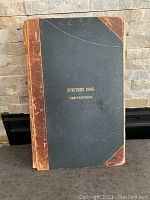 Front cover of the specimen book showing black half leather bind with gold embossed title 'Specimen Book Times Printing Co.'