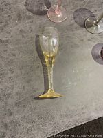Single yellow-tinted liqueur glass shown lying down to highlight transparency and condition