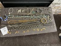 Overview photo showing the full assortment of costume jewellery laid out on a surface including necklaces, bracelets, rings, earrings, belt, and small decorative pieces.