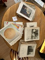 Overhead view of various vintage magazines spread out on a round table showing covers and pages with colorful and black and white images.
