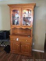 Full view of small oak buffet and hutch with leaded glass doors and wood finish.