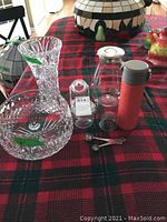 Photo showing cut crystal vase, footed crystal bowl, glass loose tea press jar, small jam jar, and red travel mug on red and green plaid tablecloth