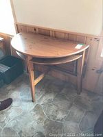 Photo of the semi-circular pine table with drop leaf fully down, showcasing the curved end and wood grain details.