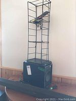 Photo showing Sony sound bar, small Sony speaker, wireless antenna on top of the speaker and a metal CD holder rack placed behind them on a wooden surface.