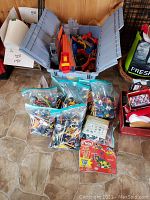 Overall view of ten large ziplock bags filled with mixed Kinex building pieces and a grey plastic tote with Hot Wheels track and cars inside