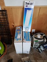 Photo of two 10ft boxes of white C Guard Profile Ice Guard and a boxed Thin-Lite 12 Volt DC Fluorescent Light Model 134.