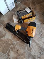 Full view of pneumatic framing nailer and two boxes of nails on floor