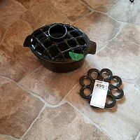 Set of cast iron woodstove steamer with lattice lid and matching trivet on tiled floor