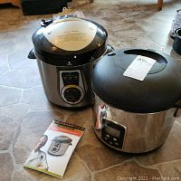 Wolfgang Puck 7 Quart Pressure Cooker and PC rice cooker with manual laid out on tiled floor