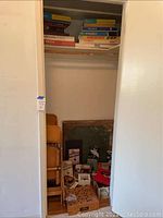 Photo showing closet with shelves filled with various vintage board games, puzzles, card table, and chairs stacked inside.