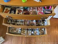 Three open drawers filled with compartmented boxes of assorted costume jewelry pieces