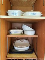 Top shelves with Corning Ware casserole dishes featuring blue cornflower pattern, white ceramic dishes