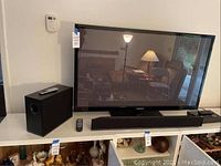 Front view of Samsung TV mounted on console with Vizio sound bar front-center and wireless subwoofer to left