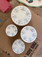 Top view of stacked dinnerware plates and saucers featuring gray floral pattern with gold trimming.