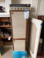 Amplifier unit atop two speakers; manual visible at base