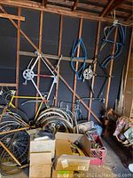 Overview of garage wall showing multiple bicycle frames mounted on studs, wheels and boxes on the floor