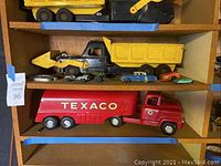 Shelf view showing dump truck on top shelf and Texaco tanker below with smaller toys between