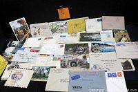 Overview photo showing a box full of assorted antique postcards, envelopes, and stamped mail from different eras and locations.