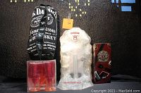 Overview of the lot showing Jack Daniels bottle bag, Smirnoff Ice light-up display, Chivas Regal tin, and box of mini margarita glasses
