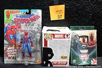 Photo of the lot showing sealed 1994 The Amazing Spider-Man action figure, Marvel Pop! Mystery box, and Marvel vs Trading Card Game starter deck